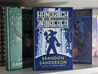 Ein Foto von einem Bücherregal, in dem das Buch Handbuch für den genügsamen Zauberer: Überleben im mittelalterlichen England von Brandon Sanderson steht.