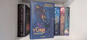 Bücherregal, im Vordergrund steht das Buch: Yumi and the Nightmare Painter
