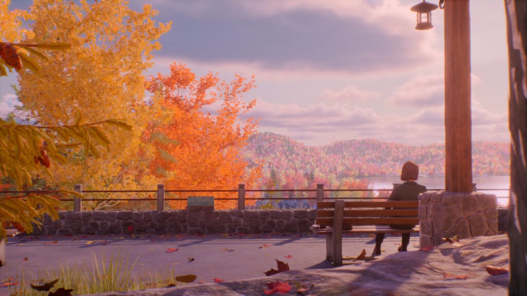 Screenshot aus Life is Strange: Reunion. Max sitzt auf einer Bank und denkt nach. Eine schöne Aussicht mit einem See, kleinen Bergen und bunter Landschaft ist in der Ferne zu sehen.